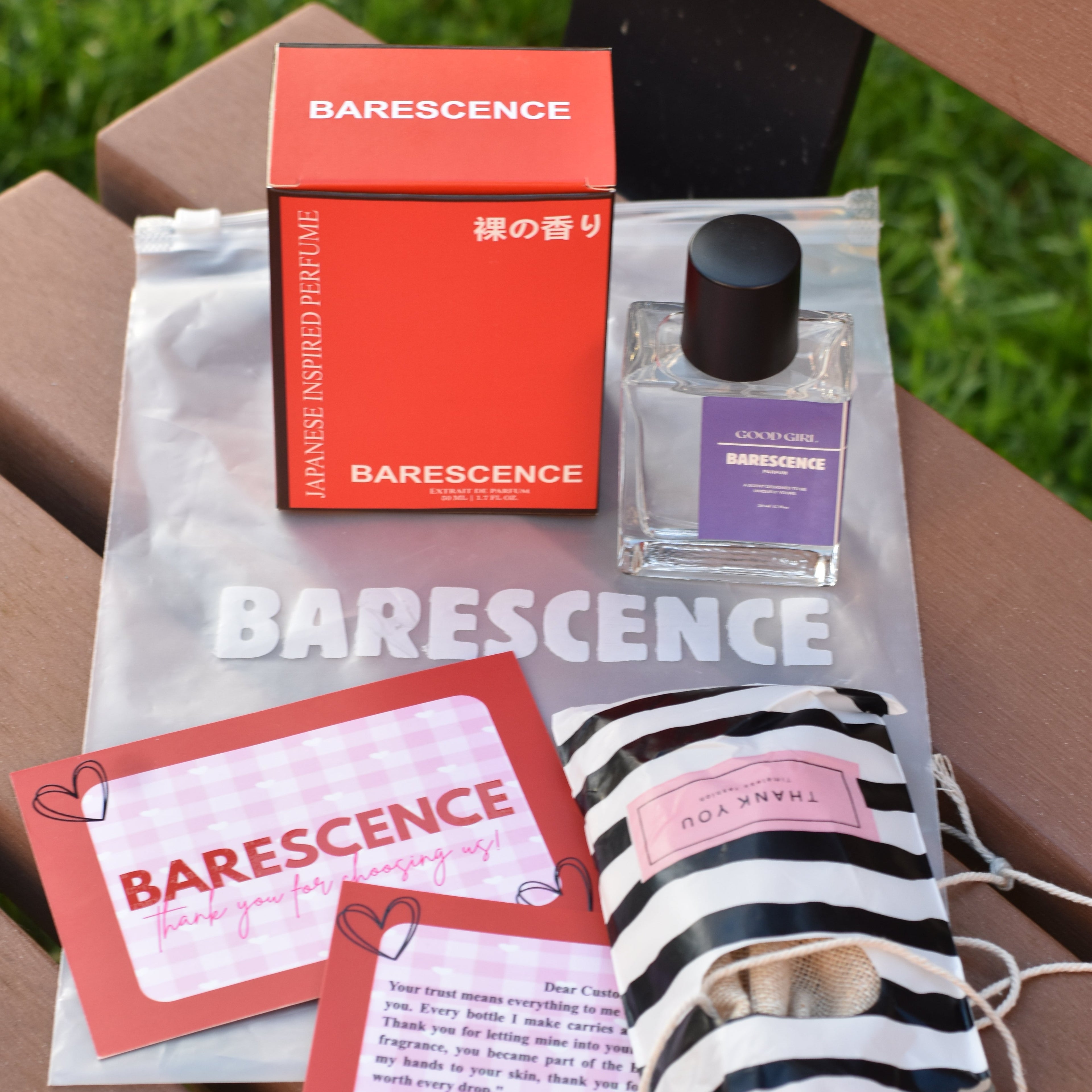 Barescence skincare products including a box, bottle, and pouch on a wooden surface with grass in the background.